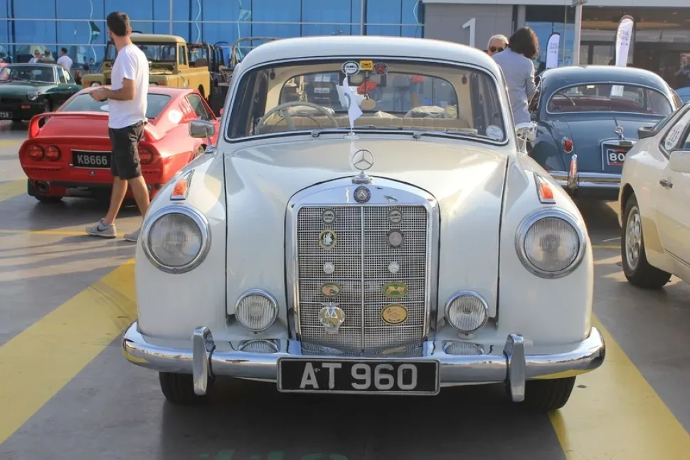 Серебристый Mercedes‑Benz спереди с декоративными эмблемами и номером AT 960