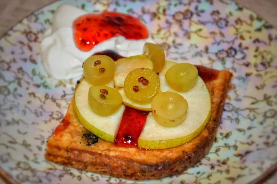 Порция запеканки с грушей и сметаной с джемом на тарелке