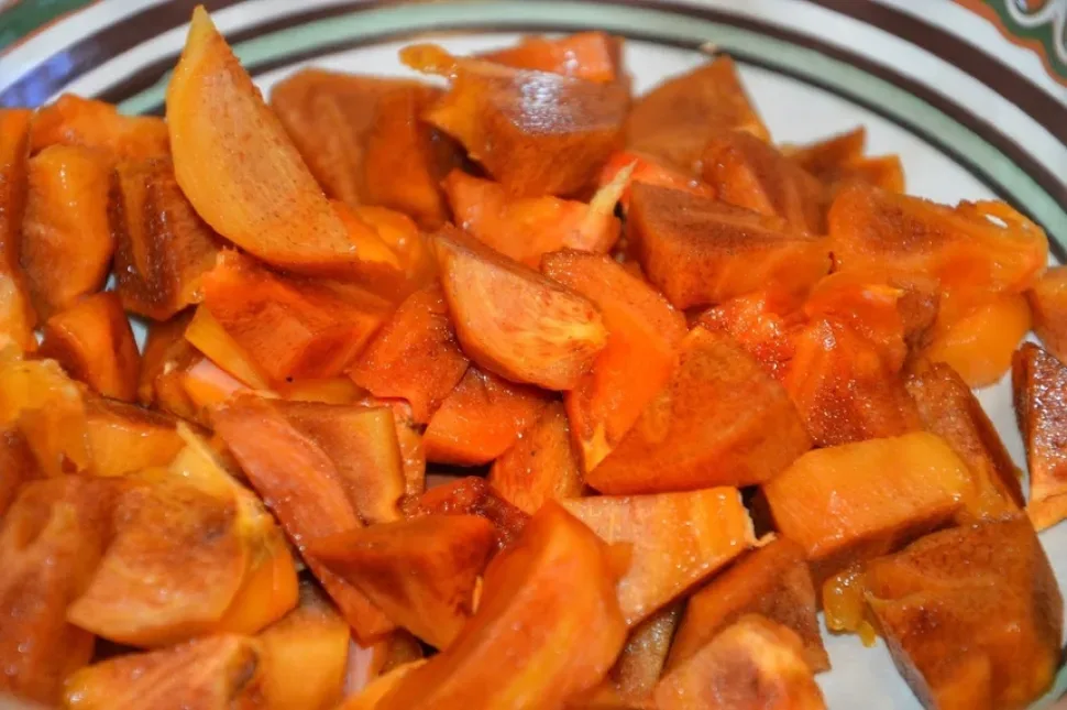 Нарезанная хурма кусочками с вынутыми косточками на доске