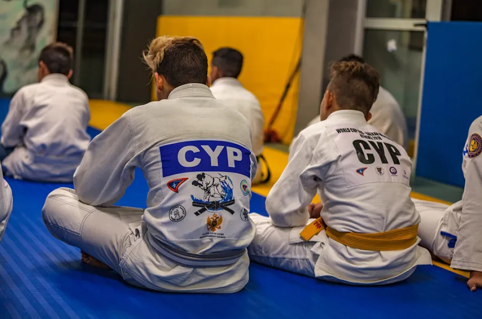 Сидящие на татами юные спортсмены в кимоно с надписью CYP Сидящие на татами юные спортсмены в кимоно с надписью CYP