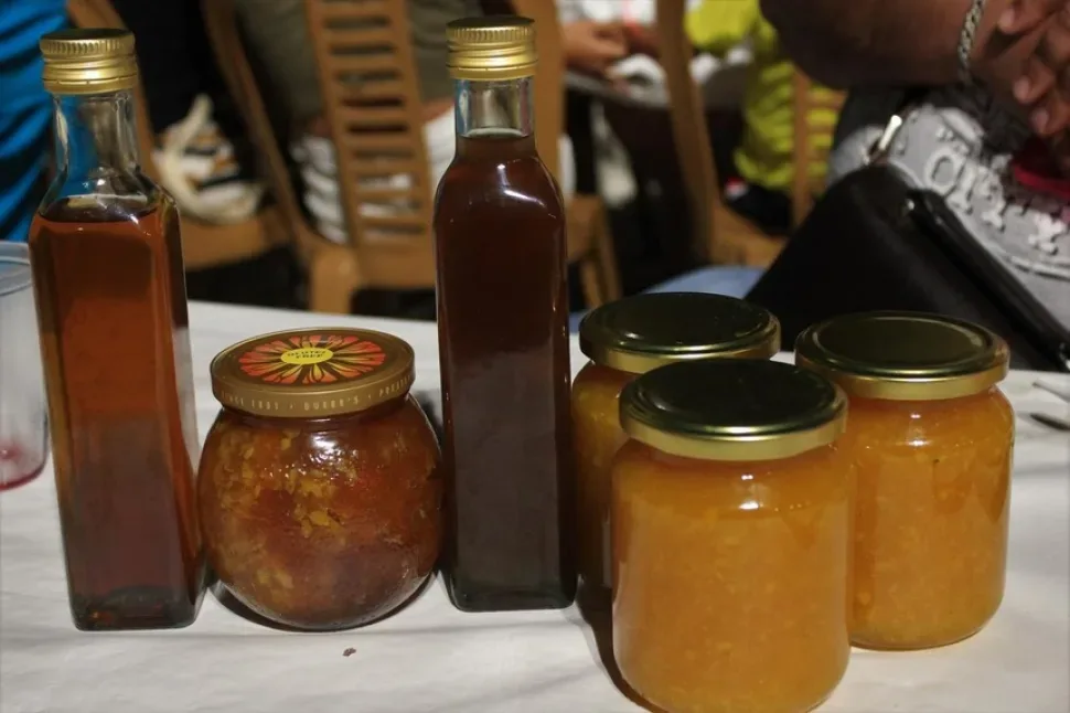 Продавец показывает бутылки домашнего сиропа и варенья гостям