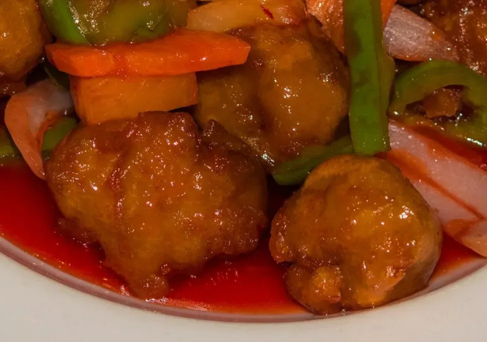 Порция риса с ананасом, овощами и кусочками курицы в кисло‑сладком соусе