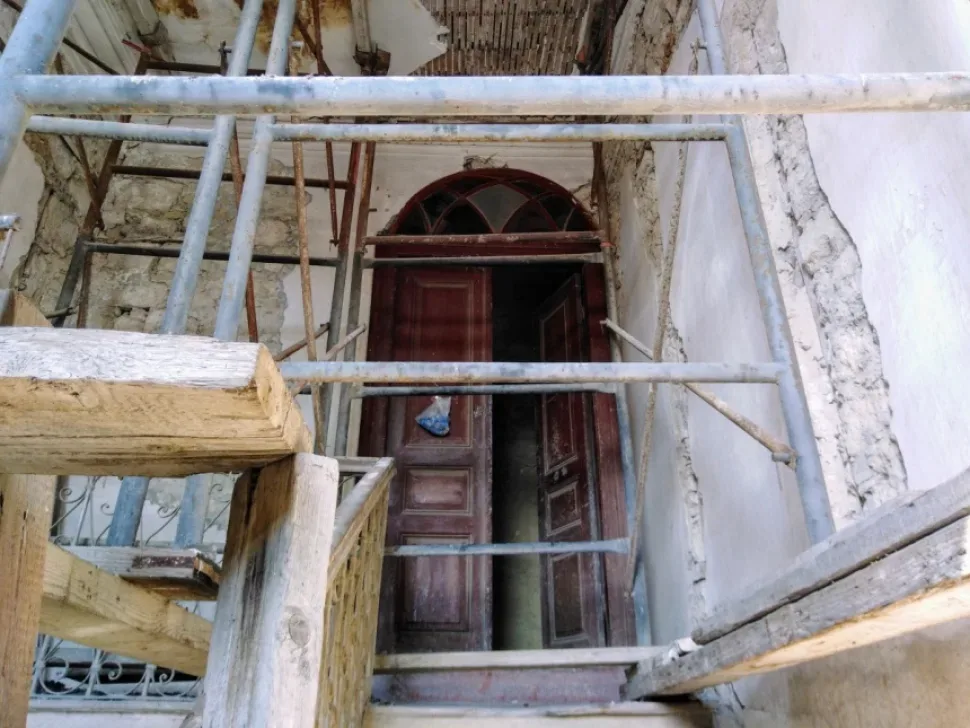 Входная дверь особняка за строительными лесами и разбитым порогом