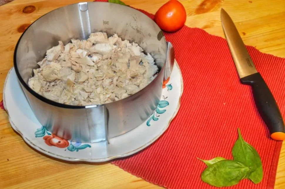 Нарезанное отварное куриное филе на разделочной доске с ножом