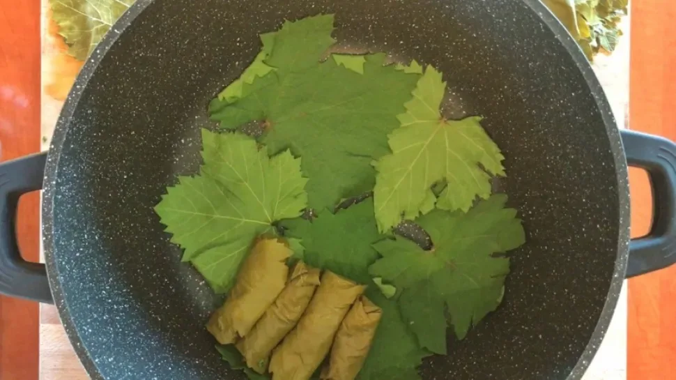 Руки сворачивают купепья на разделочной доске в аккуратные рулетики