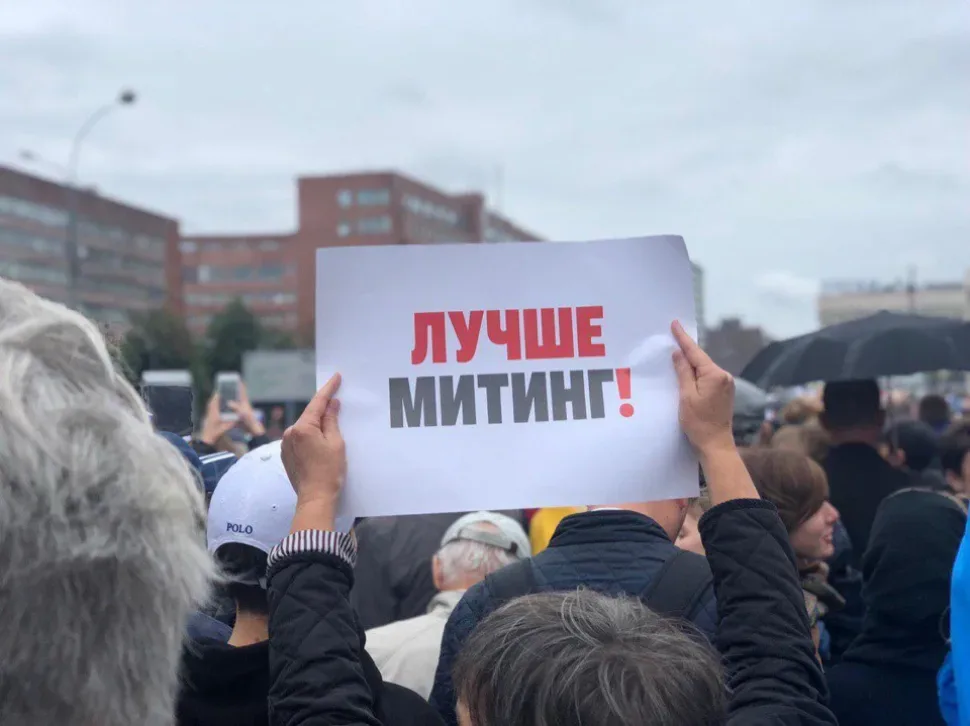 Толпа демонстрантов, один человек держит плакат «Лучше митинг! Толпа демонстрантов, один человек держит плакат «Лучше митинг!