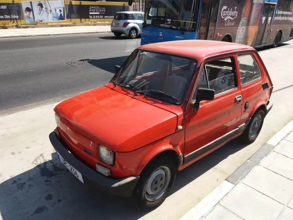 Другой ракурс красного польского Fiat 126l на городском тротуаре