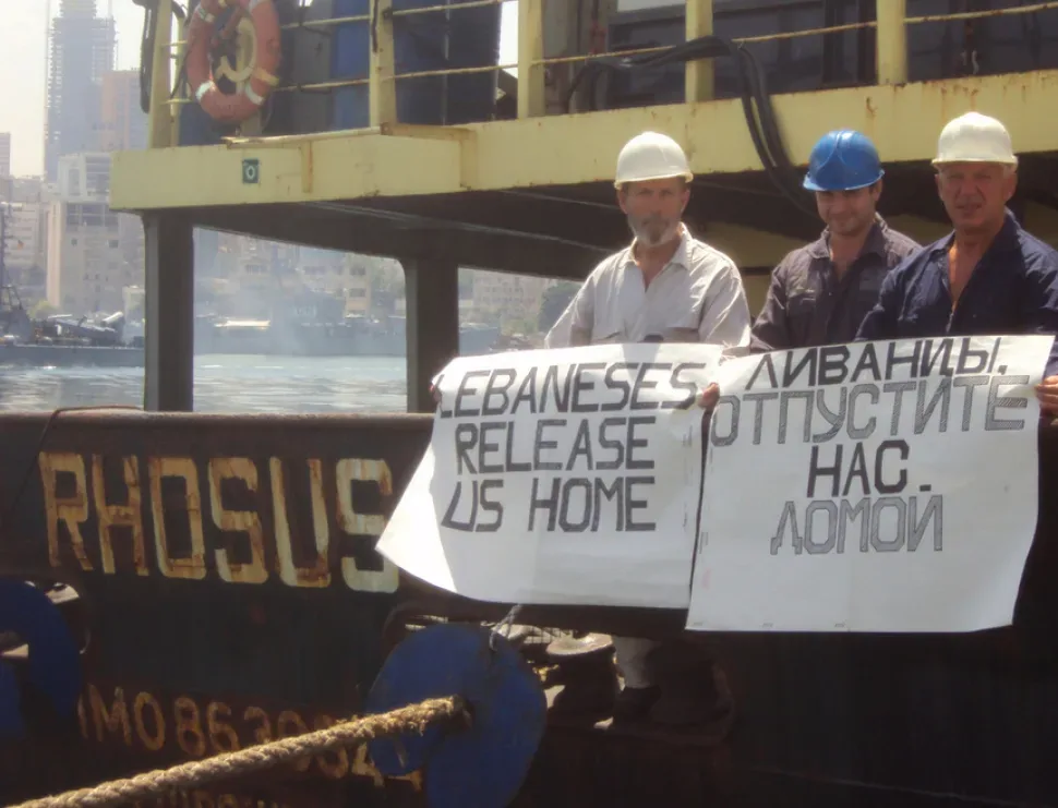 Члены экипажа у борта «Rhosus» с плакатом на английском просьба отпустить домой