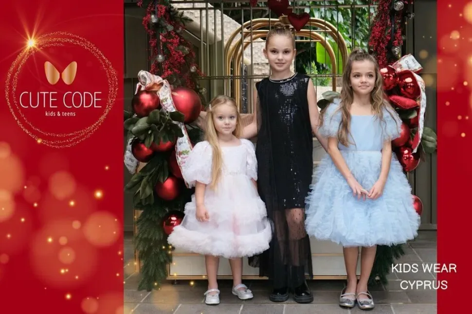 Три девочки в праздничных платьях бренда Cute Code у рождественской декорации Три девочки в праздничных платьях бренда Cute Code у рождественской декорации