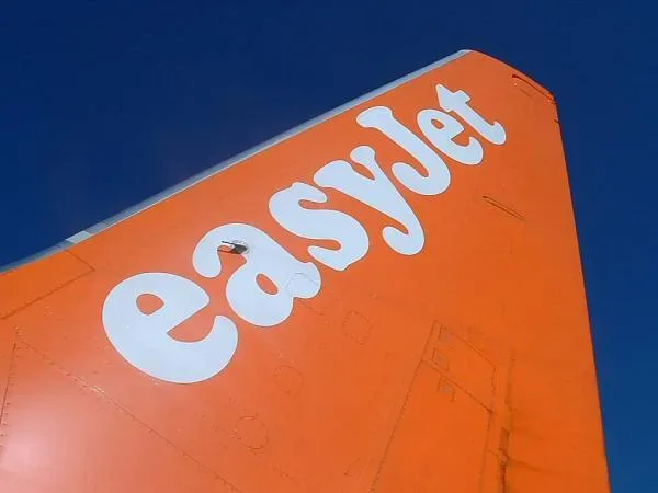 Фрагмент хвоста и ливреи самолета easyJet оранжевого цвета с названием авиакомпании