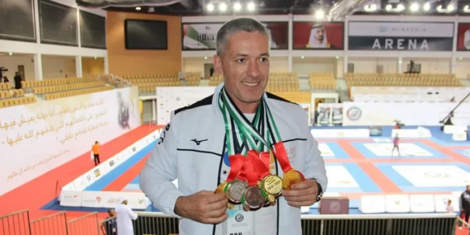 Детская команда с тренером позирует на подиуме чемпионата с медалями