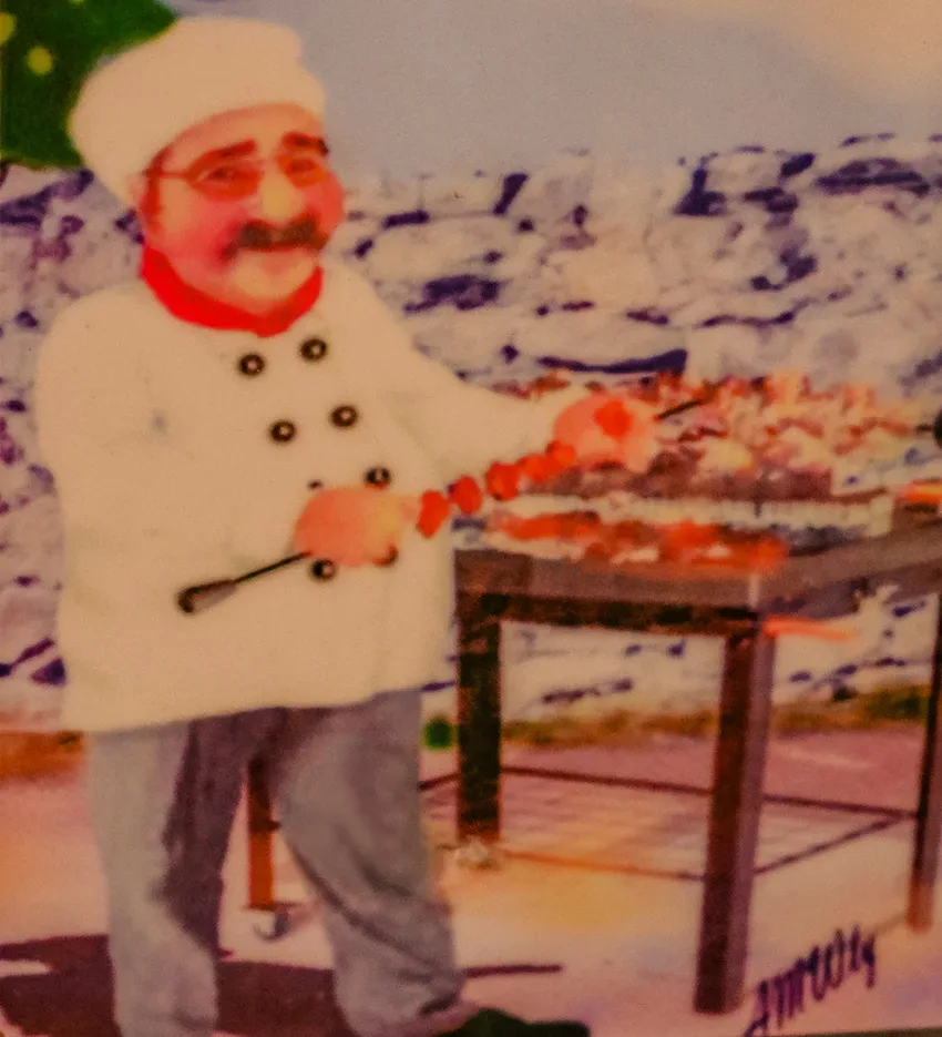 Повар-гриль в белом кителе жарит шашлык у моря
