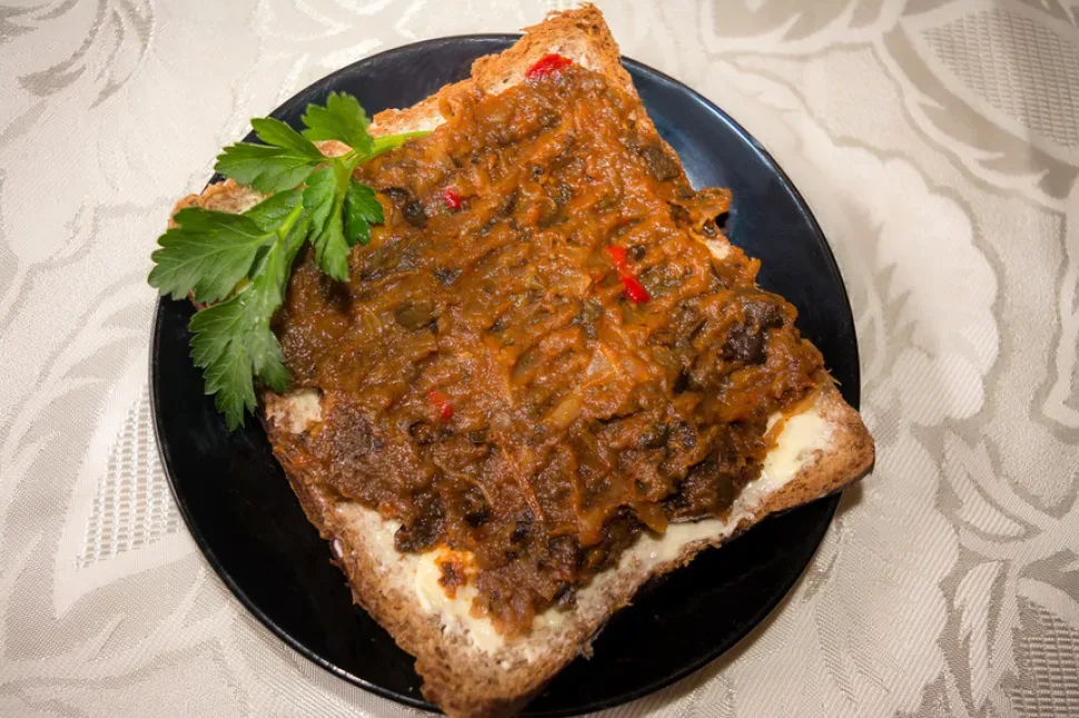 Кусок хлеба с баклажанной икрой и веточкой петрушки сверху