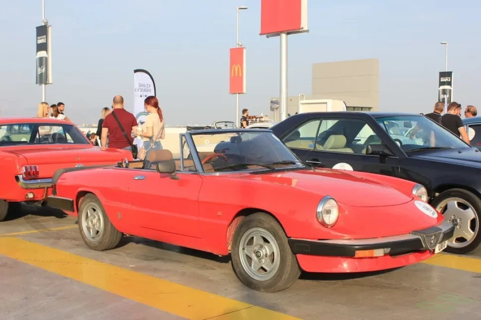 Красный кабриолет Alfa Romeo на стоянке ретро‑автомобилей