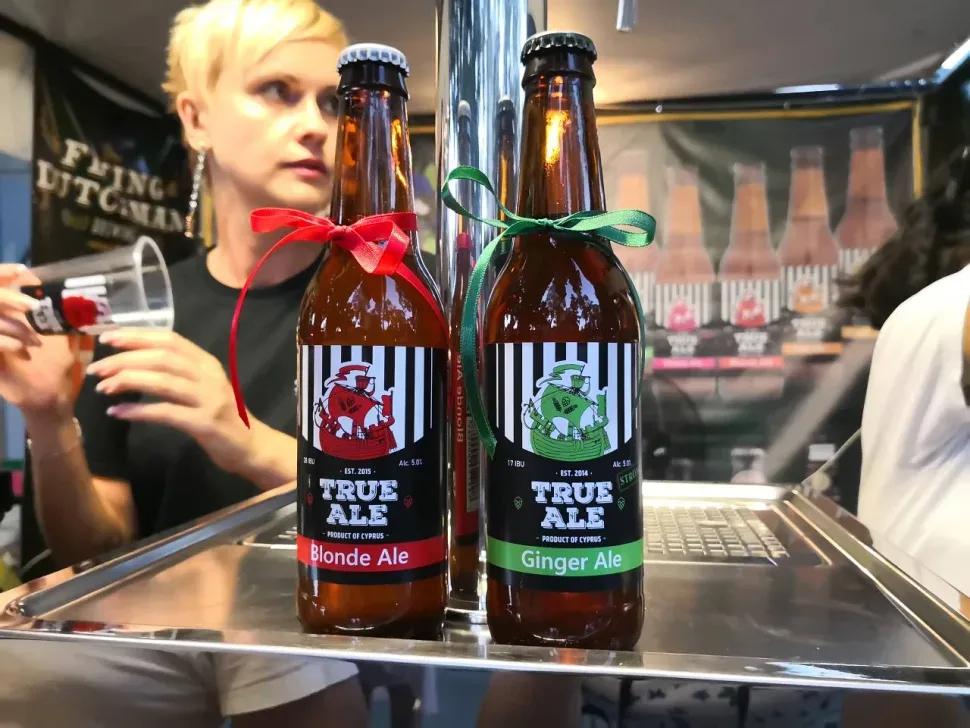 Пара пивоваров за стойкой разливает бутылочное пиво марки True Ale
