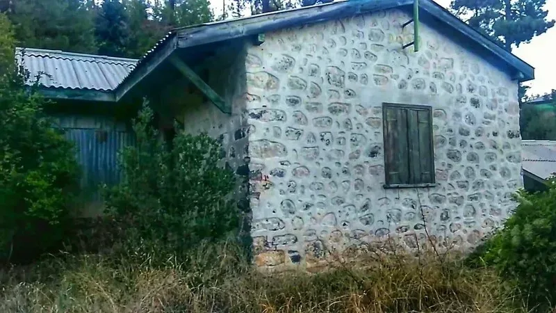 Каменный дом в Амиантосе с закрытым оконным проёмом и заросшей оградой Каменный дом в Амиантосе с закрытым оконным проёмом и заросшей оградой