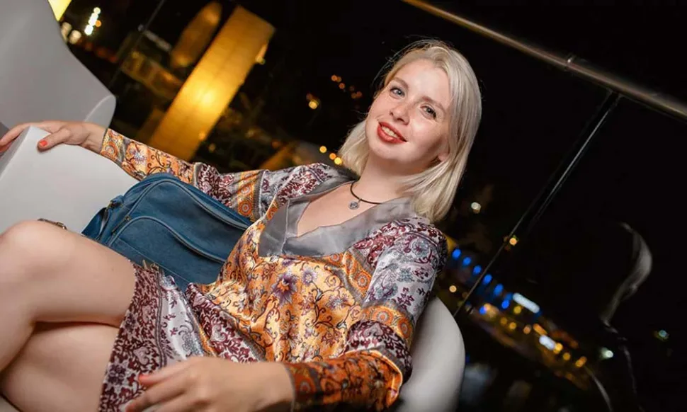Мужчина в розовой рубашке стоит на фоне колонки и гостей