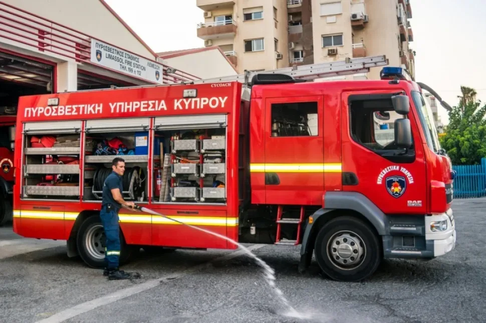 Пожарный у красной автоцистерны Лимасол проверяет подачу воды Пожарный у красной автоцистерны Лимасол проверяет подачу воды