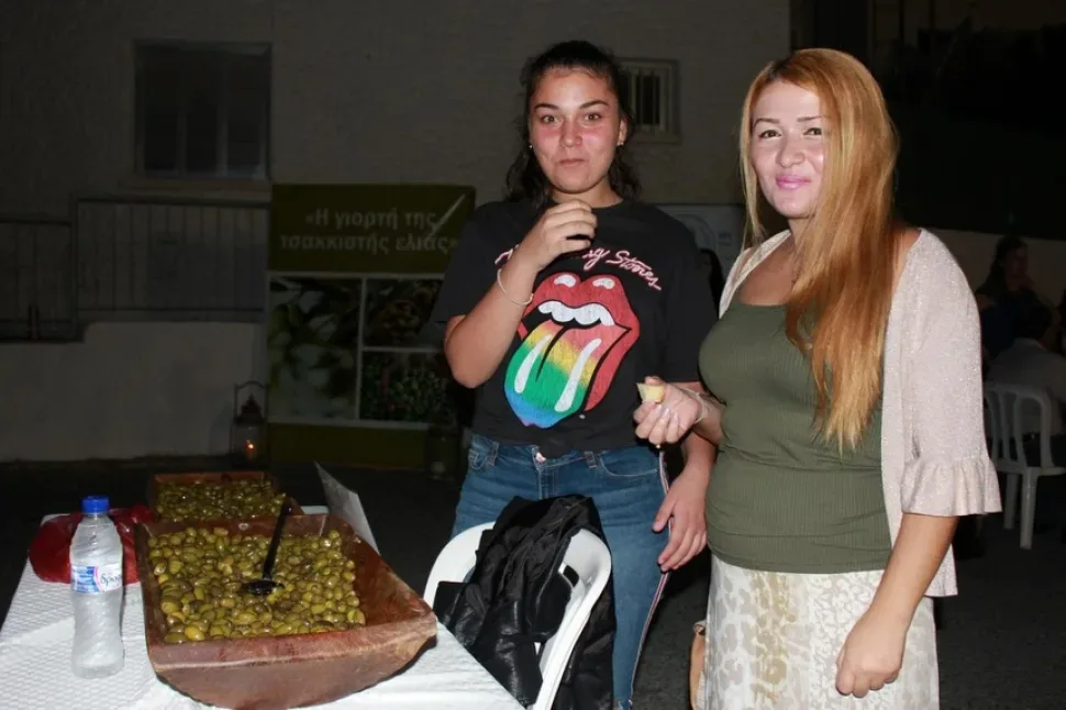 Девушки берут маринованные оливки с деревянного лотка на фестивале Девушки берут маринованные оливки с деревянного лотка на фестивале