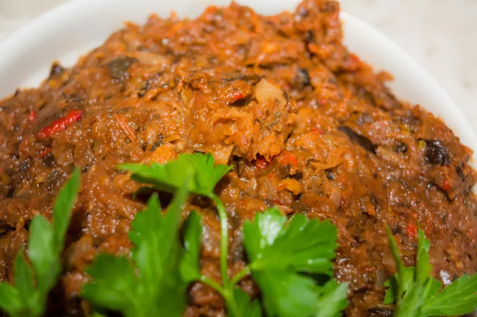 Крупный план текстуры готовой баклажанной икры с кусочками овощей