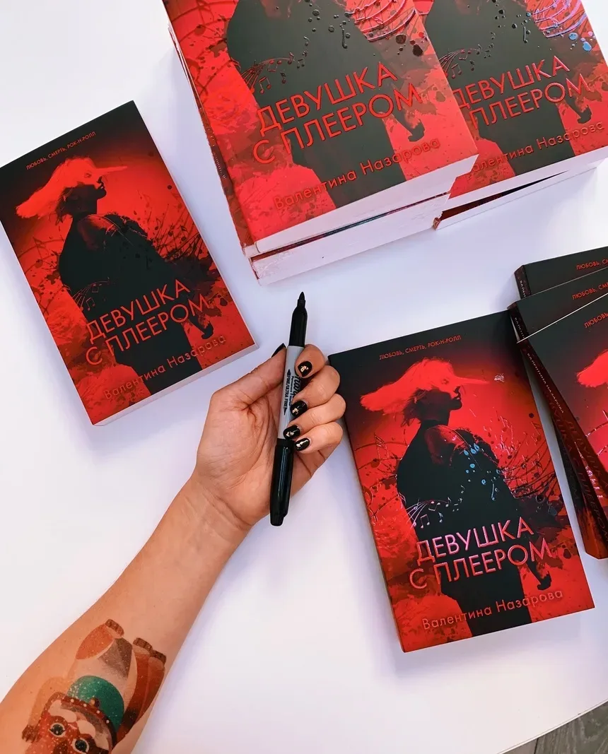 Стопка книг «Девушка с плеером» и рука с маркером для автографа Стопка книг «Девушка с плеером» и рука с маркером для автографа