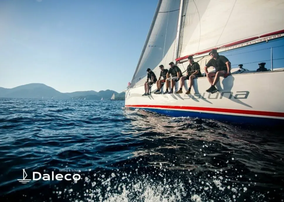 Яхта Daleco с курсантами на бортовой лавке в море Яхта Daleco с курсантами на бортовой лавке в море