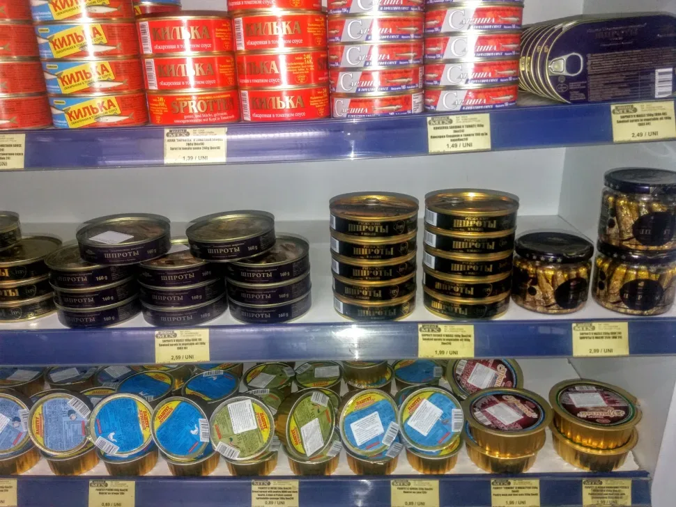 Консервы шпрот и кильки в томатном соусе на витрине магазина Консервы шпрот и кильки в томатном соусе на витрине магазина