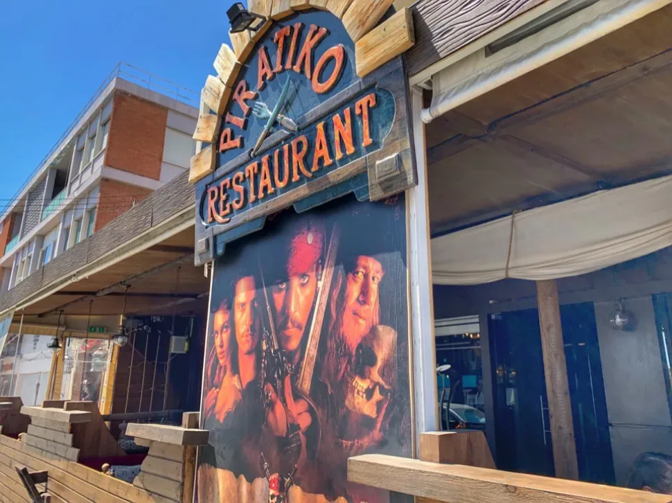 Уличный вывеска и фасад ресторана Piratiko Restaurant с постером фильма