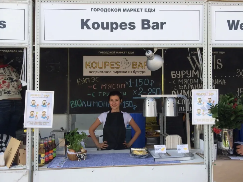 Киоск Koupes Bar на городском маркете еды с продавщицей за прилавком