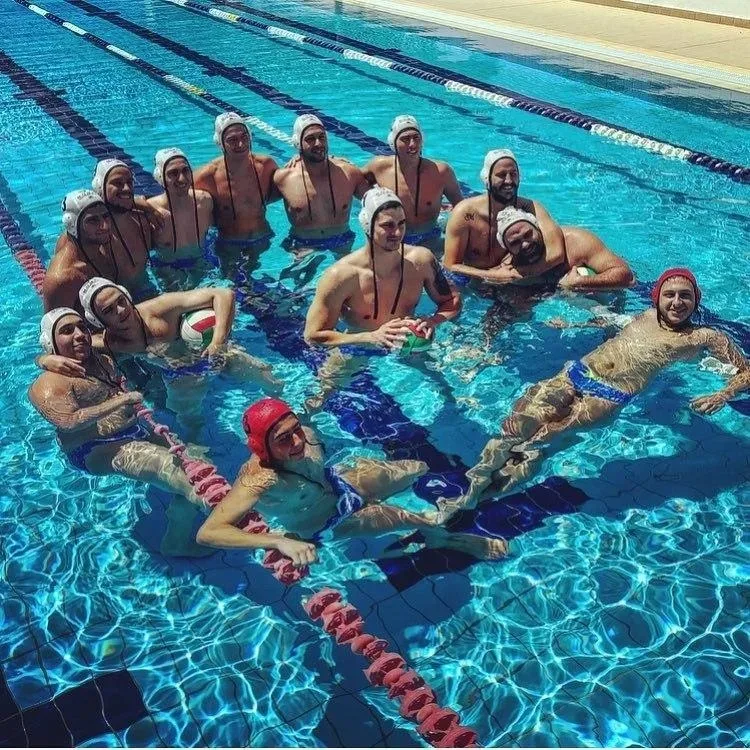 Команда игроков водного поло позирует в бассейне