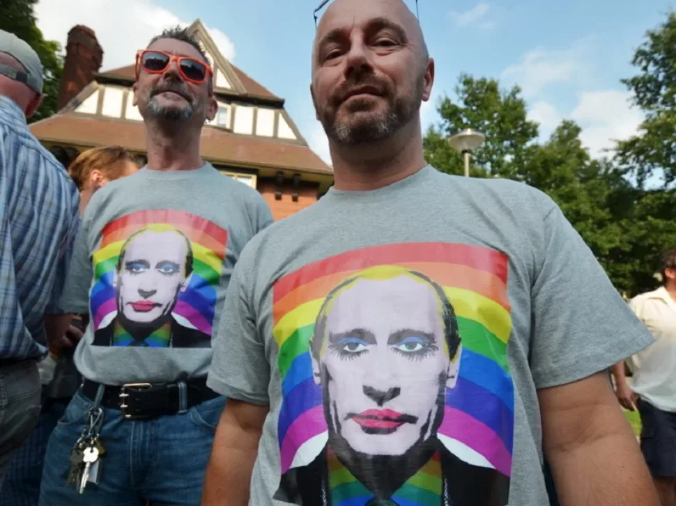 Мужчины в футболках с портретом политика и радужным фоном на митинге