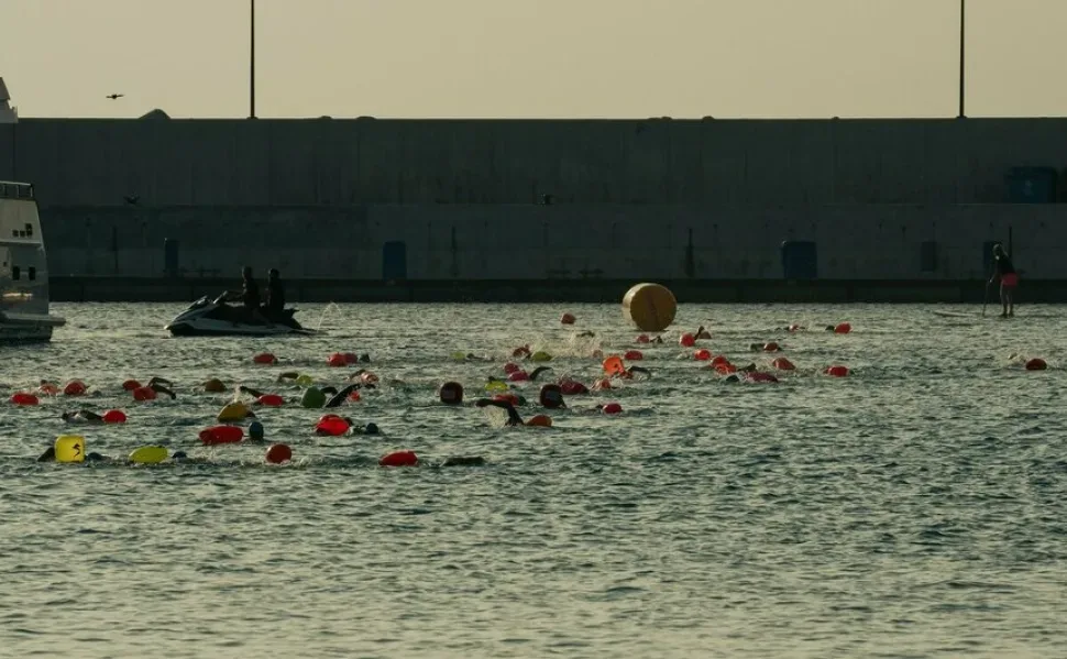 Пловцы в открытом море с разноцветными аварийными буйками в воде Пловцы в открытом море с разноцветными аварийными буйками в воде