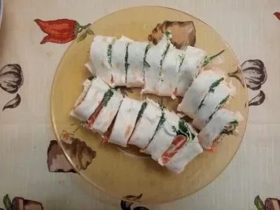 Нарезанные роллы «Дракон Куриса» с красной рыбой, огурцом и укропом на тарелке