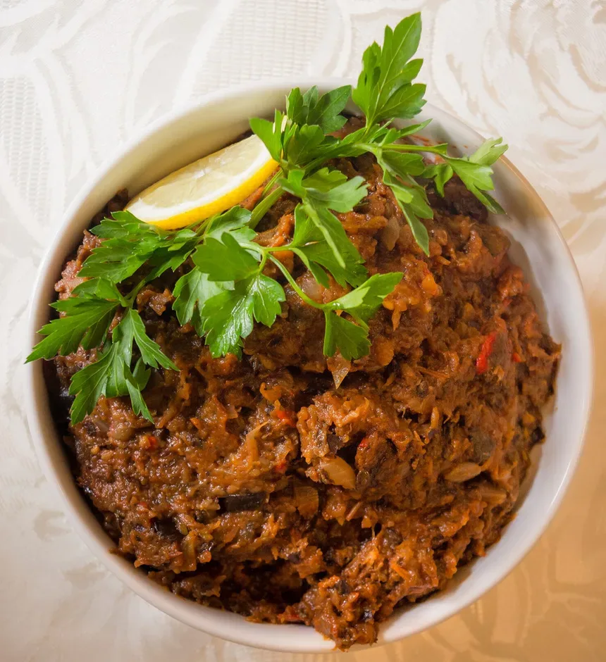 Крупный план тёплой баклажанной икры с видимыми кусочками перца