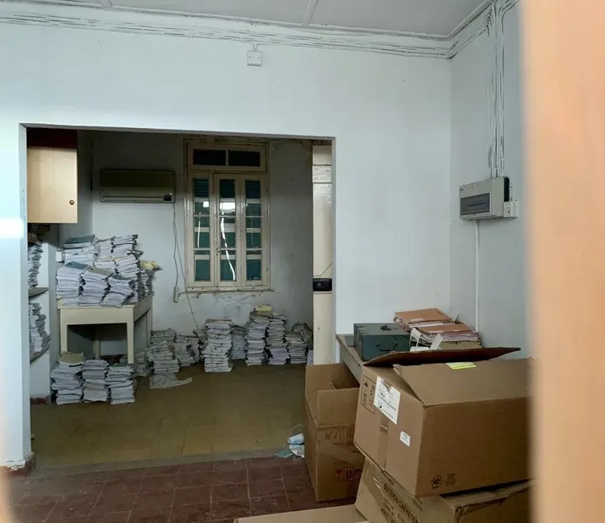 Комната лепрозория с архивными стопками бумаг и коробками на полу