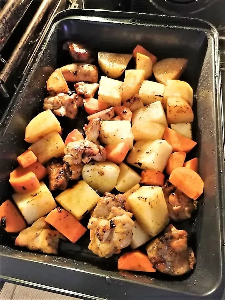 Обжаренные кусочки картофеля, моркови и мяса в металлическом противне Обжаренные кусочки картофеля, моркови и мяса в металлическом противне