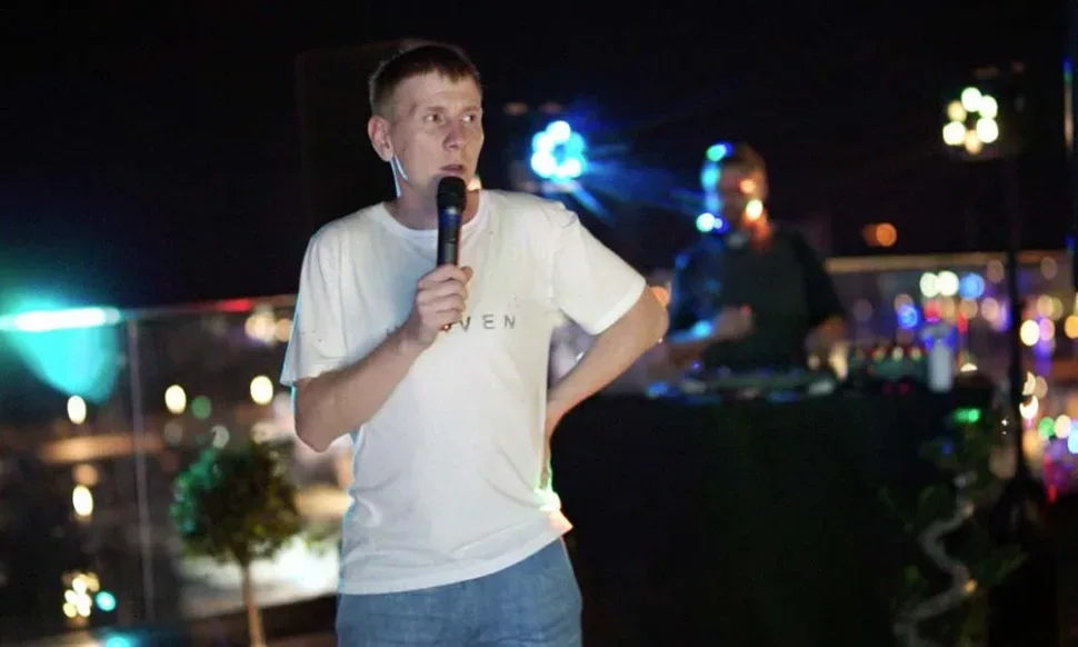 Ведущий с микрофоном выступает на ночной Sunset Rooftop Party