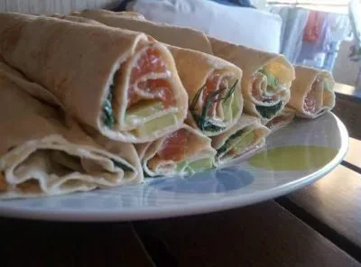 Процесс сворачивания ролла с мягким сыром и красной рыбой в лаваше