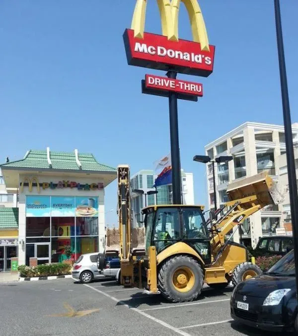Вывеска McDonald's над парковкой с погрузчиком