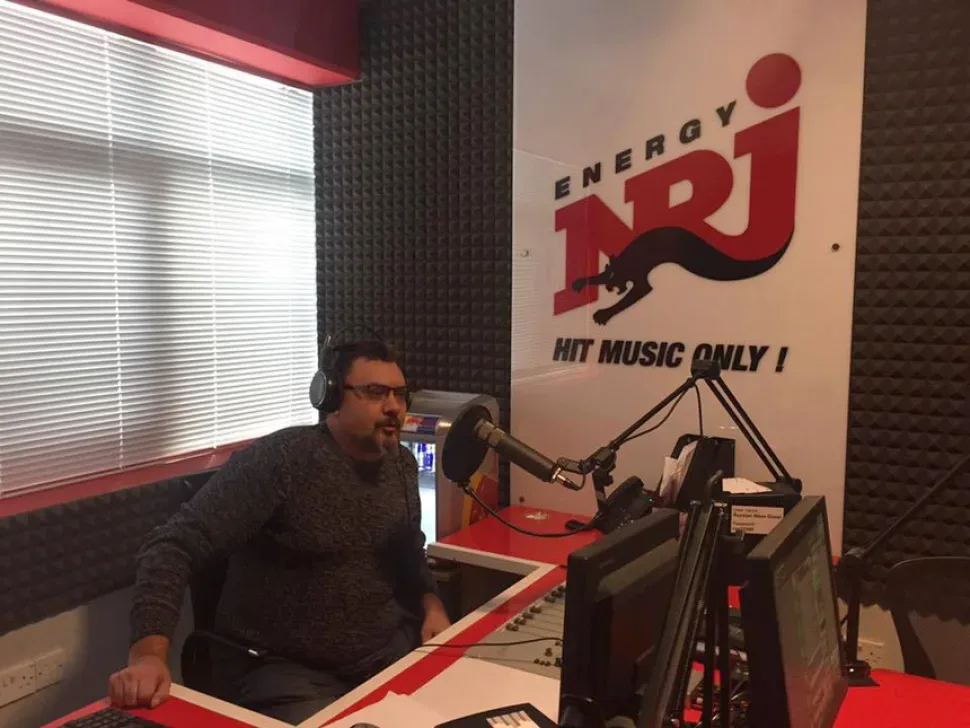 Ведущий в радиостудии NRJ в наушниках у микрофона