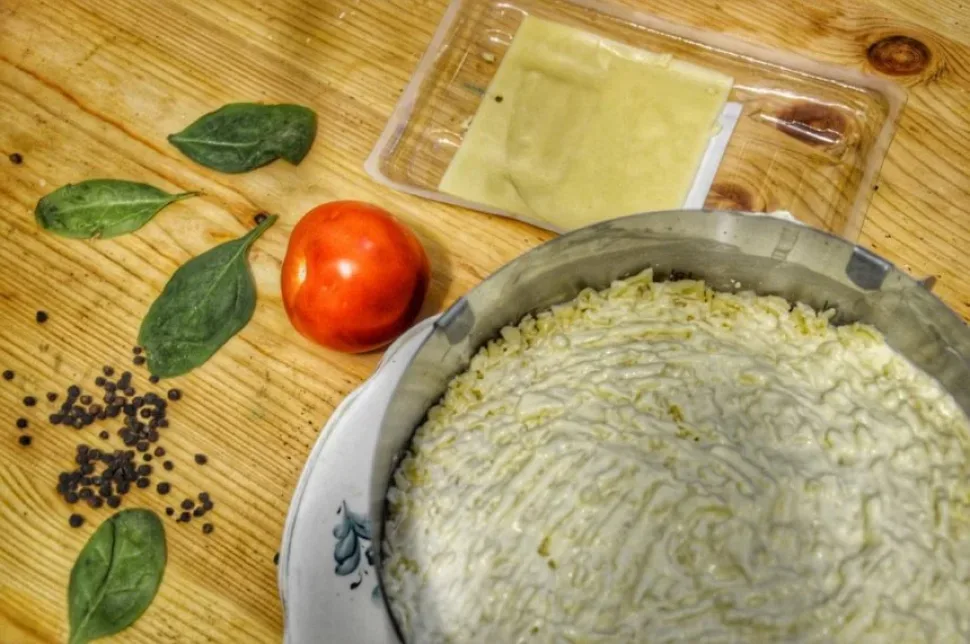 Пластинки твердого сыра в упаковке рядом с овощами на столе