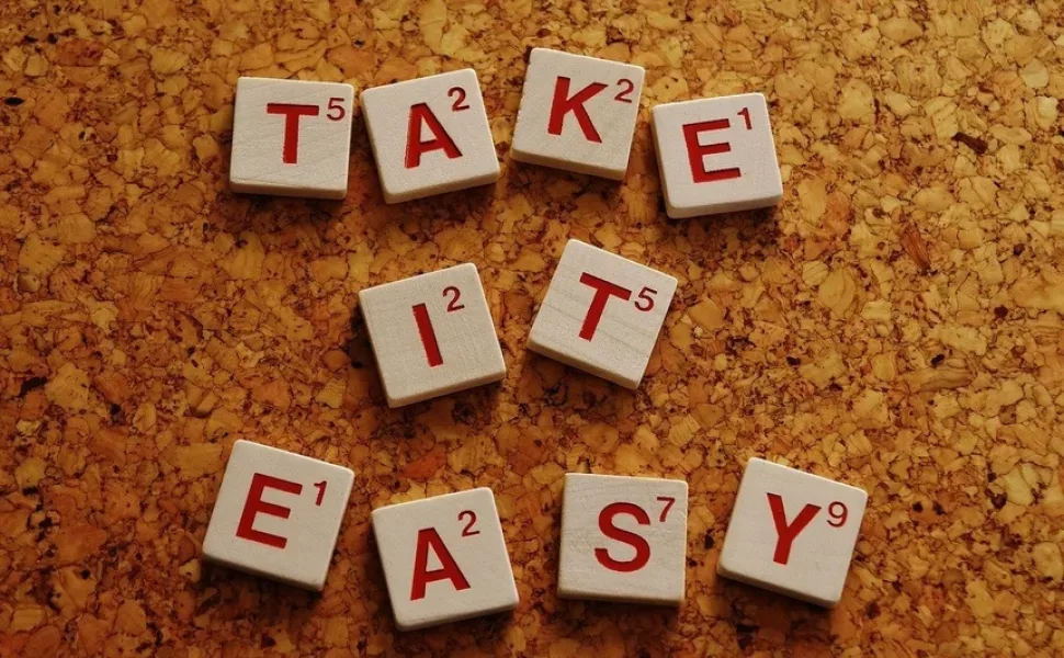 Кубики с буквами, составляющие фразу Take It Easy на пробковой доске
