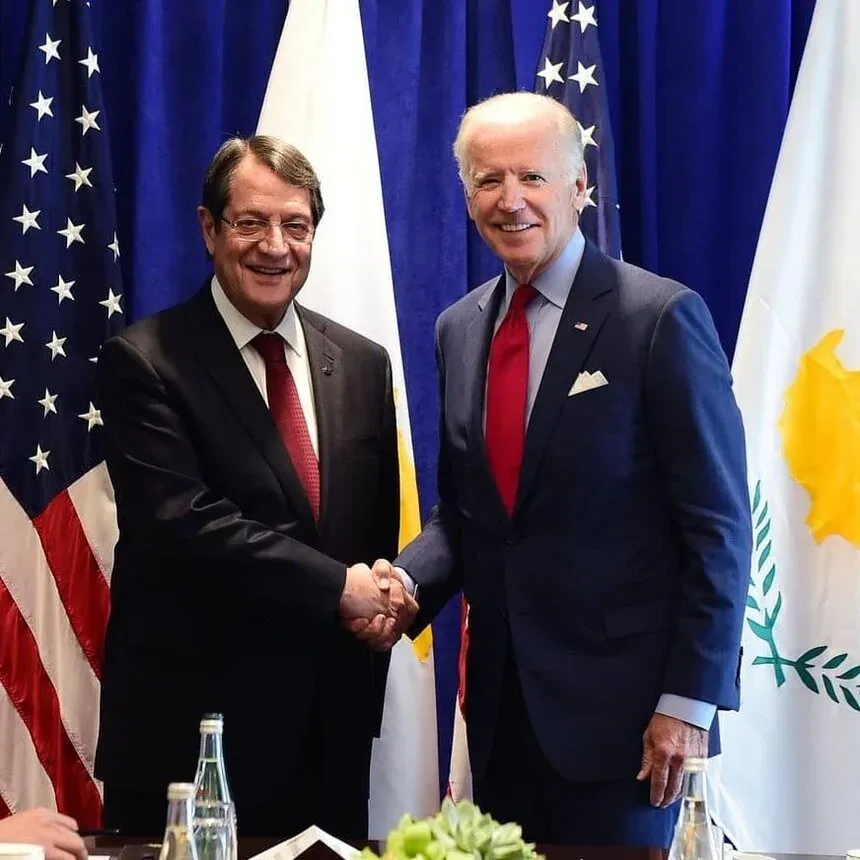 Два политика пожимают руки на фоне флагов США и Кипра