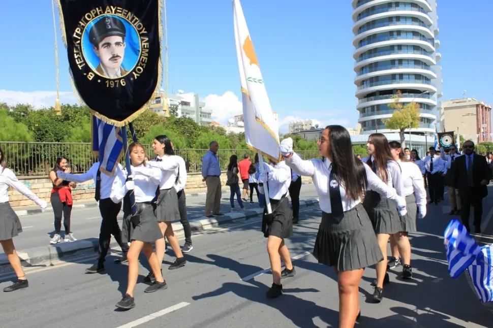 Школьники идут по центральной улице города в парадной форме и с флагами