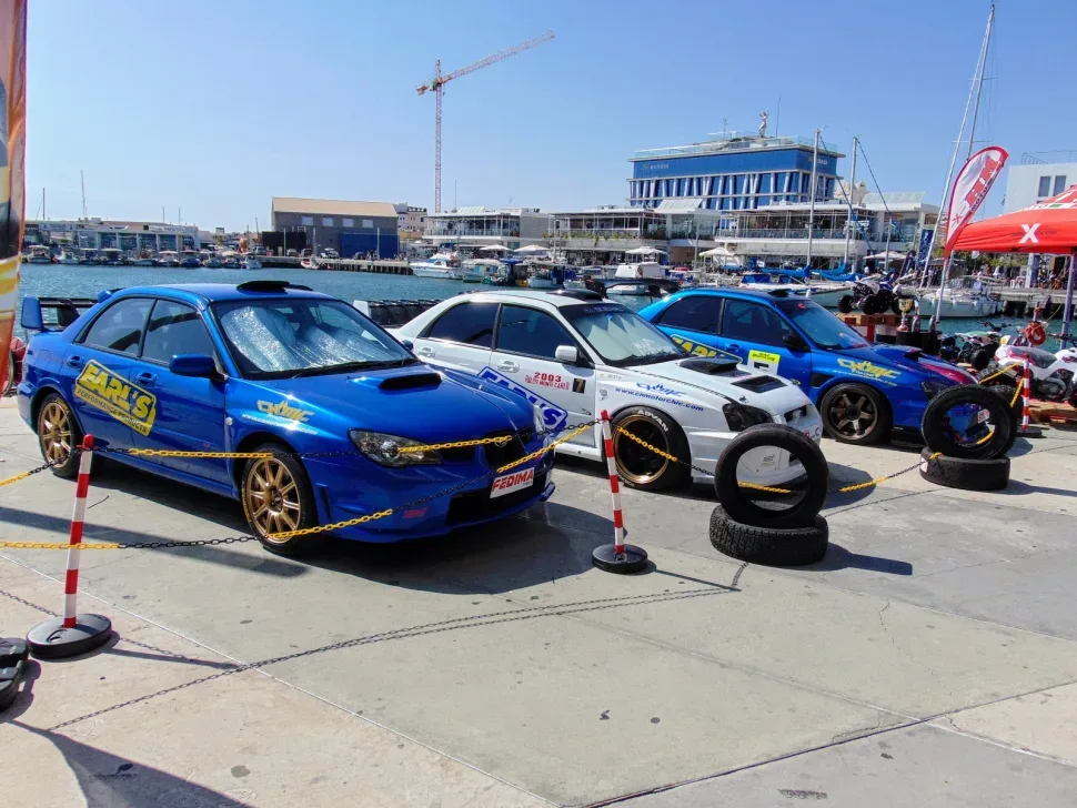 Ряд раллийных и спортивных автомобилей у набережной в марине Ряд раллийных и спортивных автомобилей у набережной в марине